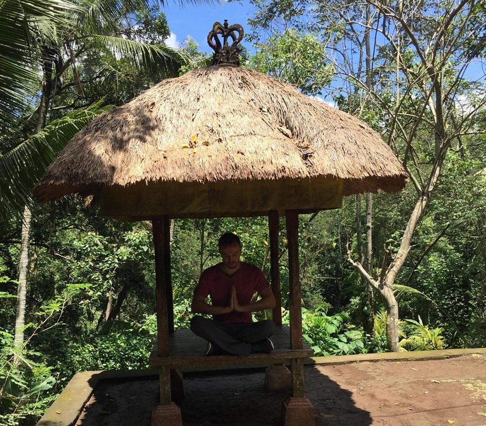 Bali'de orman içinde saz çatılı kamelyada oturan kişi